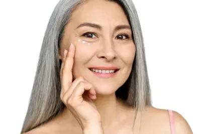 Confident mature woman with beautiful silver hair applying under-eye treatment, demonstrating effective Kansas City anti-aging solutions from Aesthetics For Women. Experience premium skincare services in KC for mature skin, including Missouri's finest eye