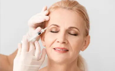 Elegant mature woman receiving premium neurotoxin injection treatment at Kansas City's Aesthetics For Women clinic. Expert Missouri medical professional administering precise anti-aging therapy for smoother skin and reduced wrinkles.