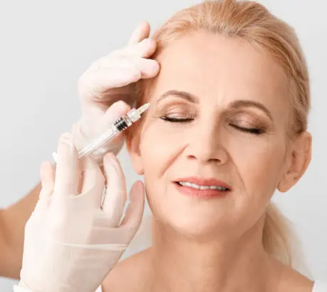 Elegant mature woman receiving premium neurotoxin injection treatment at Kansas City's Aesthetics For Women clinic. Expert Missouri medical professional administering precise anti-aging therapy for smoother skin and reduced wrinkles.